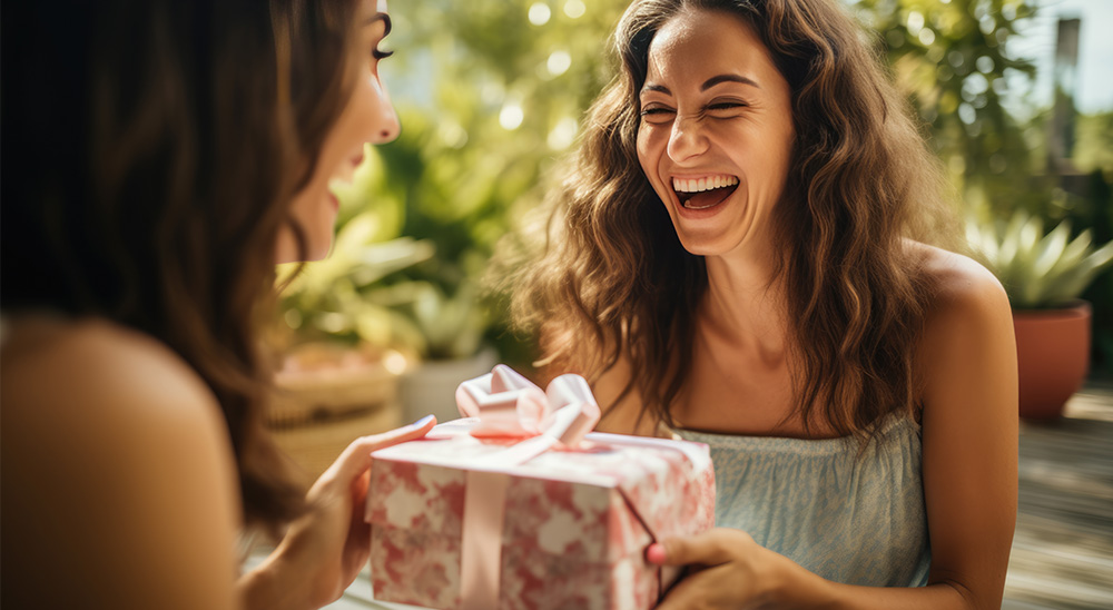 Nasmejana žena daje prijatelju poklon.