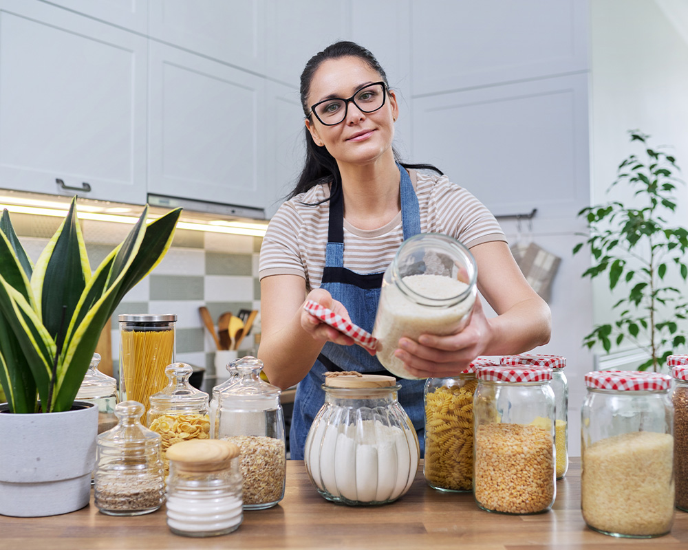 Žena u kuhinji pokazuje tegle za skladištenje suve hrane