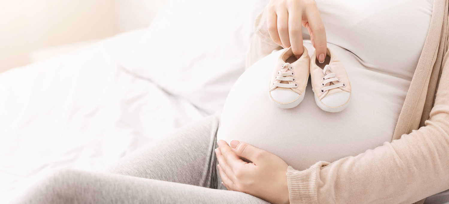 Trudnica drži na stomaku bebeće cipelice