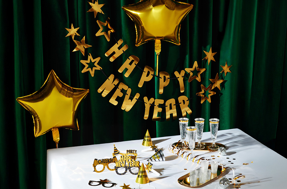 Sto ukrašen za Novu godinu, sa balonima, čašama i zlatnim ukrasima.