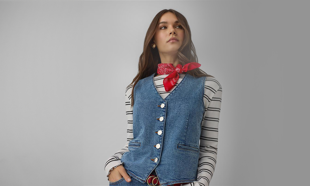 Žena nosi plavi džins prsluk i crvenu bandanu oko vrata.